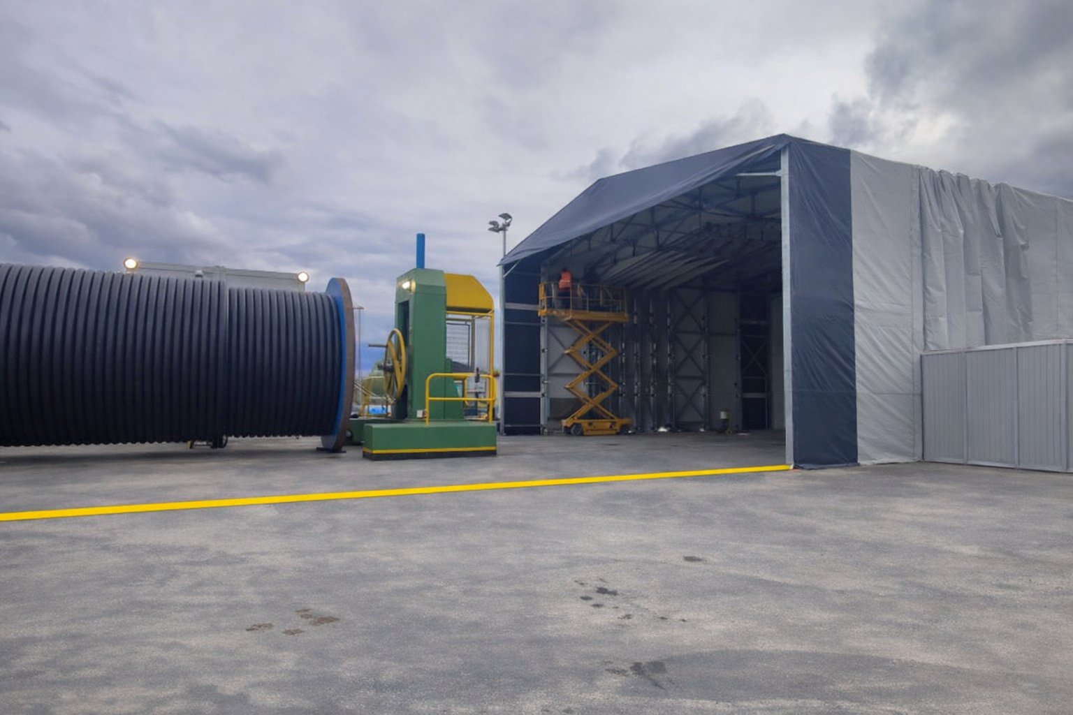 Bâtiment rétractable industriel à moitié replié pour stockage vrac avec accès latéral et structure mobile sur rails