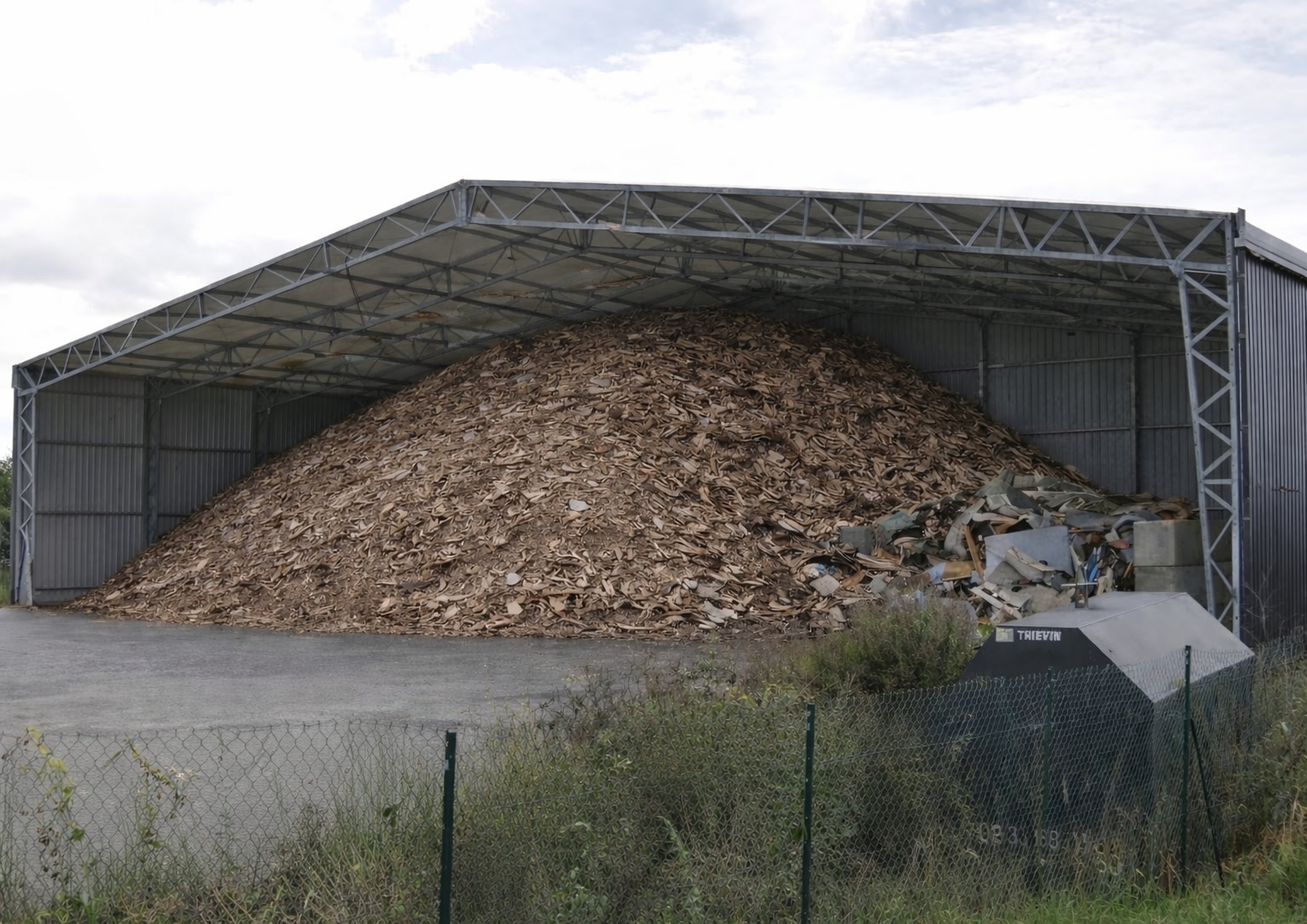 Hangar de stockage vrac industriel ouvert avec accumulation de bois ou déchets en vrac sous structure métallotextile