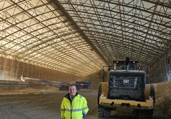 Stockage de vrac en intérieur dans un bâtiment industriel portuaire avec tas de matériaux sous charpente métallique