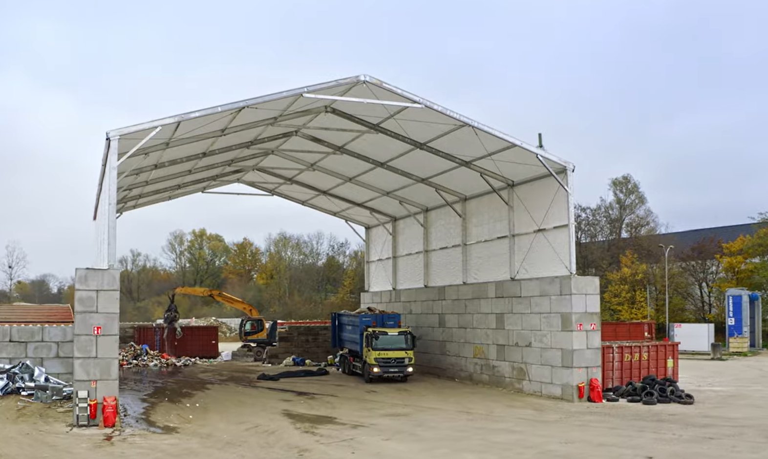 Bâtiment industriel deux pans sur blocs béton LEGO pour stockage vrac sable gravier  déchets avec structure métallo textile avec  fondation légères