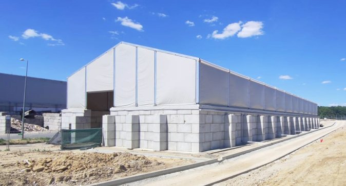 Structure métallo textile deux pans avec murs béton empilables pour stockage industriel sans génie civil